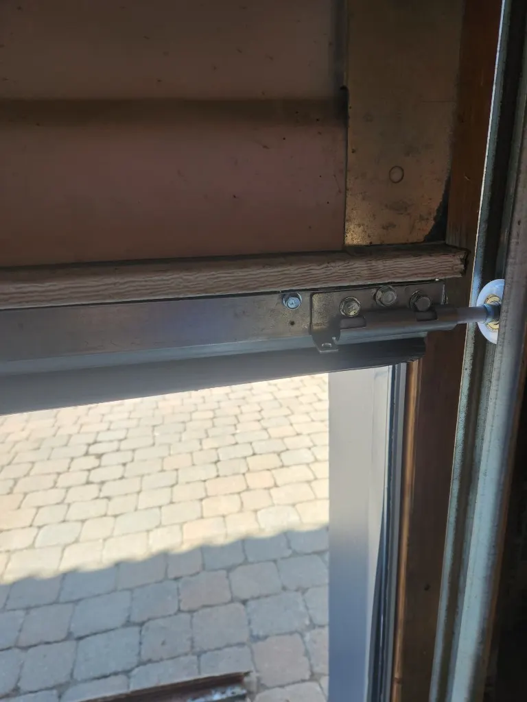 Close-up of garage door bottom weather seal with aluminum retainer and black rubber U-seal, professional installation