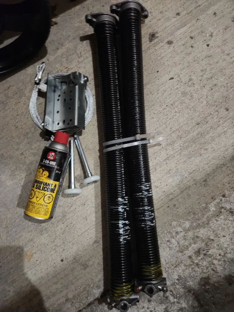 Garage door repair parts laid out for a complete service — springs, cables, rollers, and lubricant by GDS Ottawa