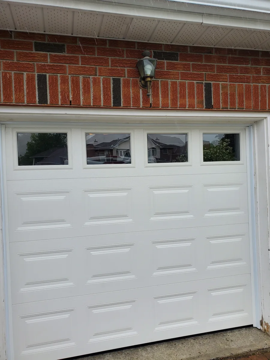New white raised-panel garage door with top windows installed at a brick home in Carp Ontario