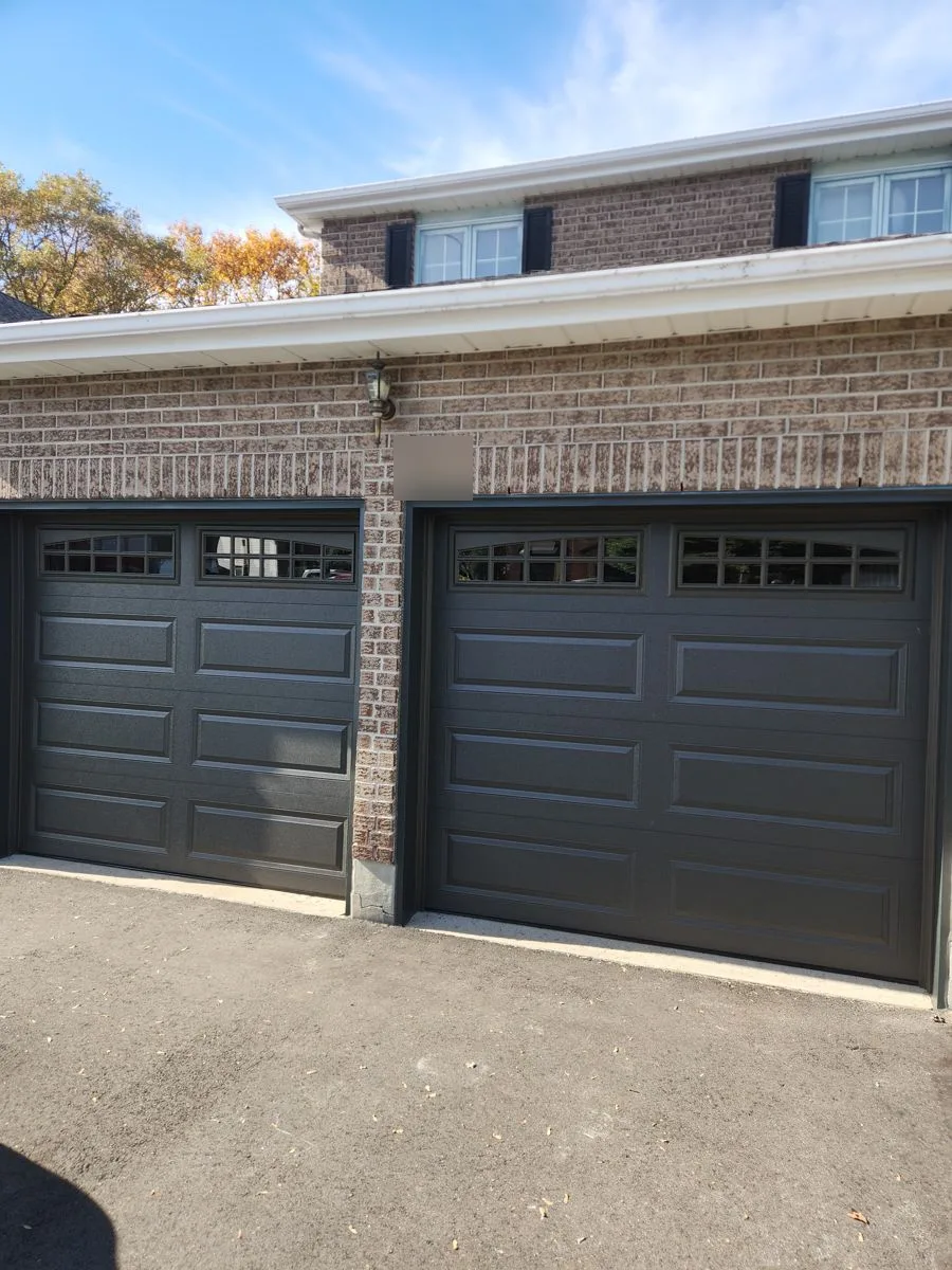 Two new black raised-panel garage doors with windows installed on a Hunt Club home in Ottawa