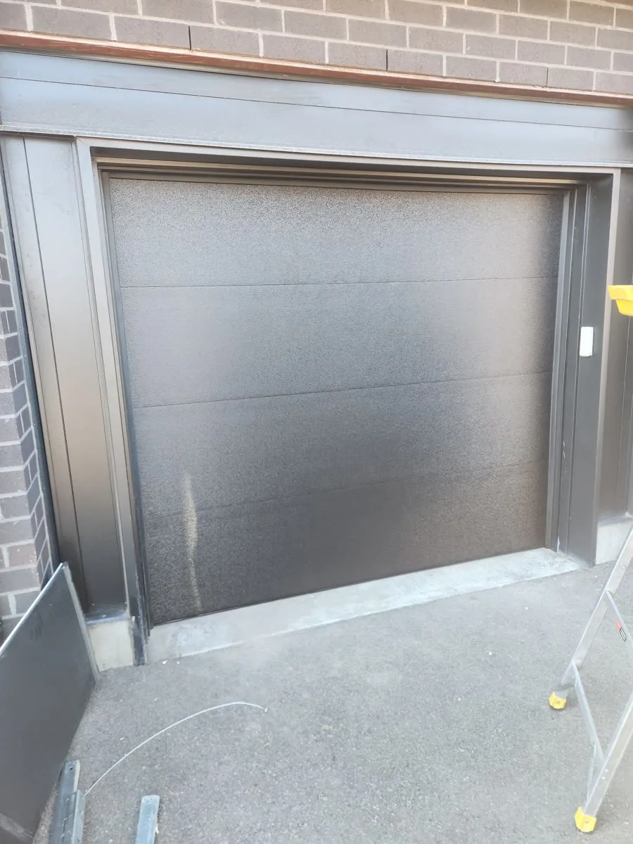 New black flush-panel garage door installed on a Hunt Club townhome in Ottawa