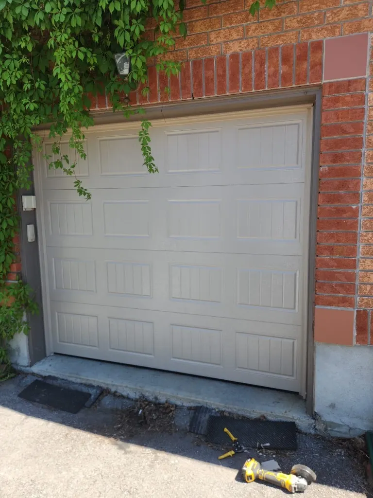 New beige carriage-style garage door installed at a brick home in Manotick Ontario