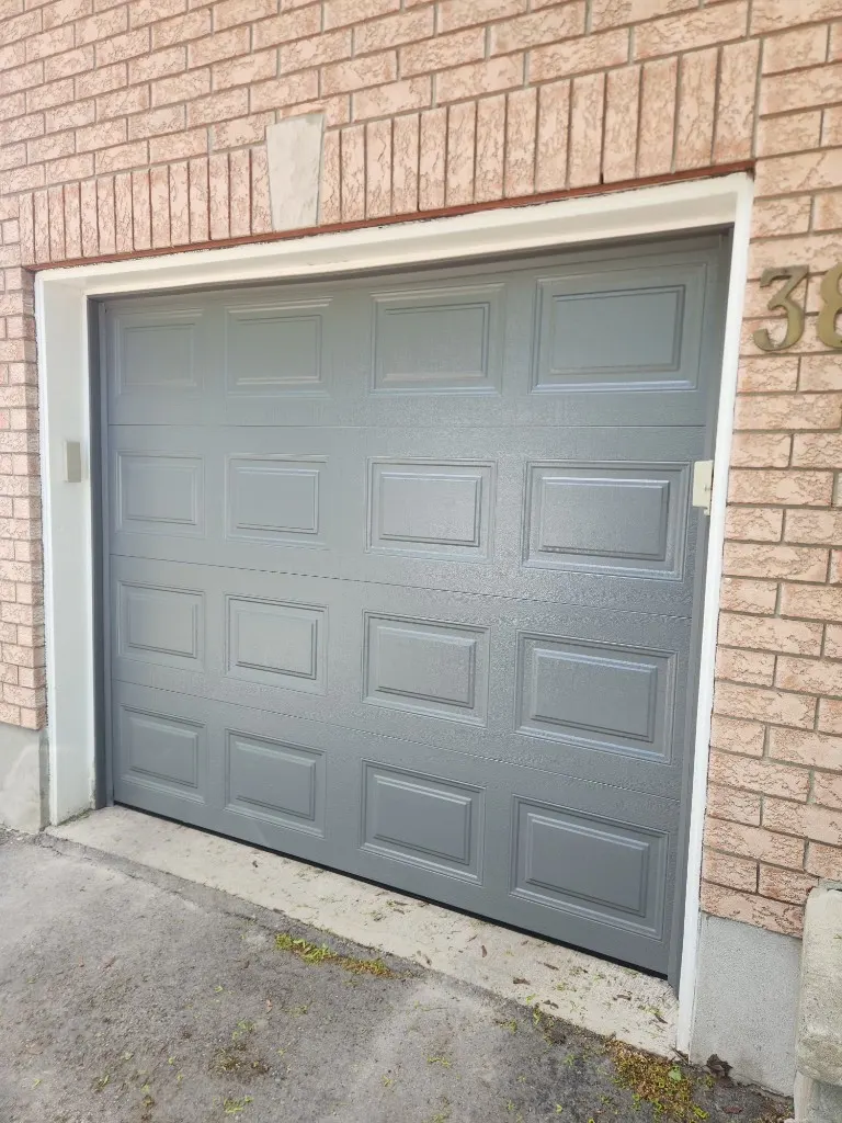 New grey raised-panel garage door installed at a brick home in Stittsville Ontario
