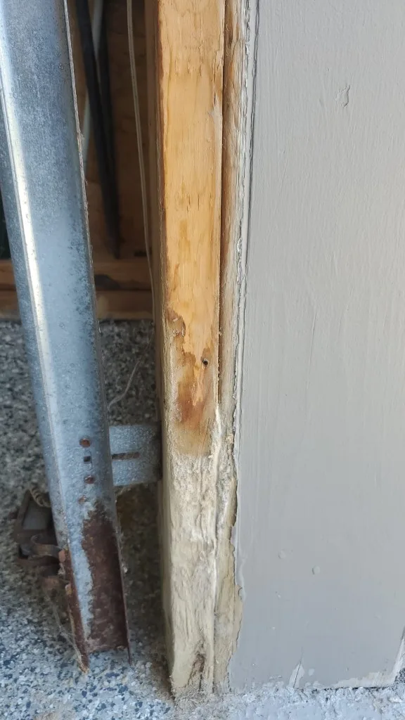 Before photo: rotting garage door jamb with failing filler and rusted track bracket in Ottawa