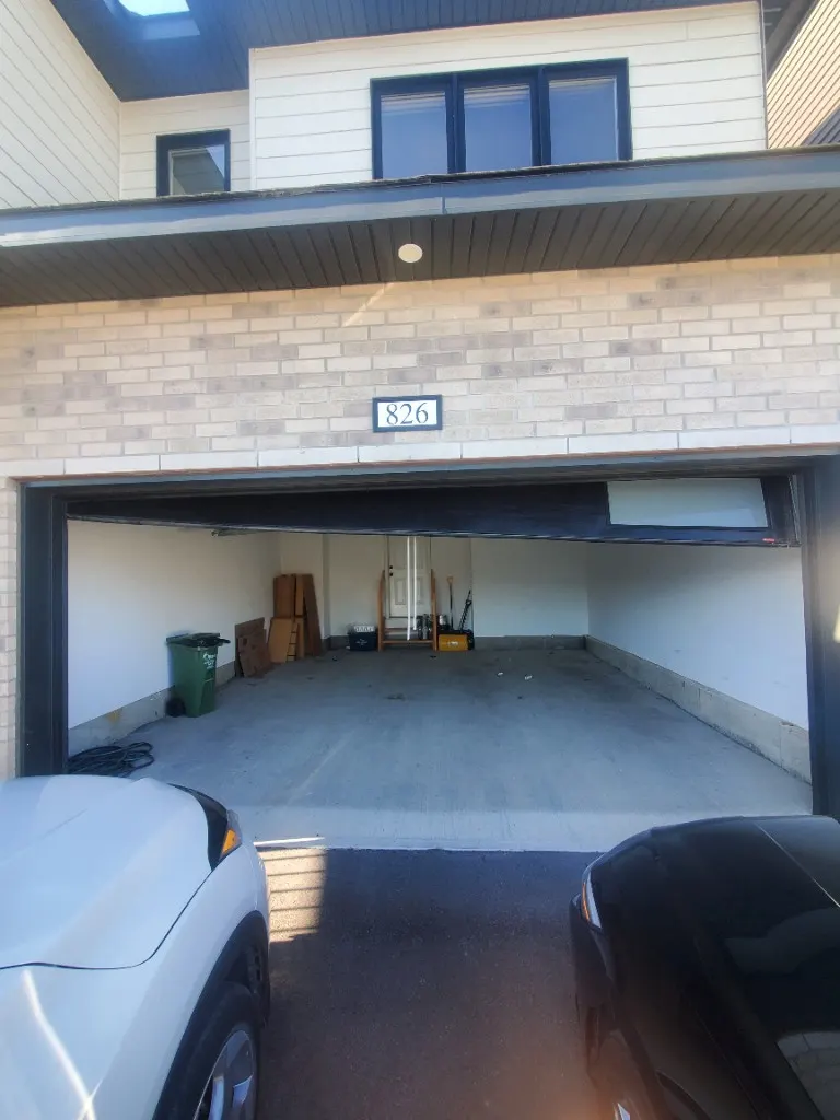 Off-track garage door emergency repair in Barrhaven — black door hanging crooked after jumping the tracks