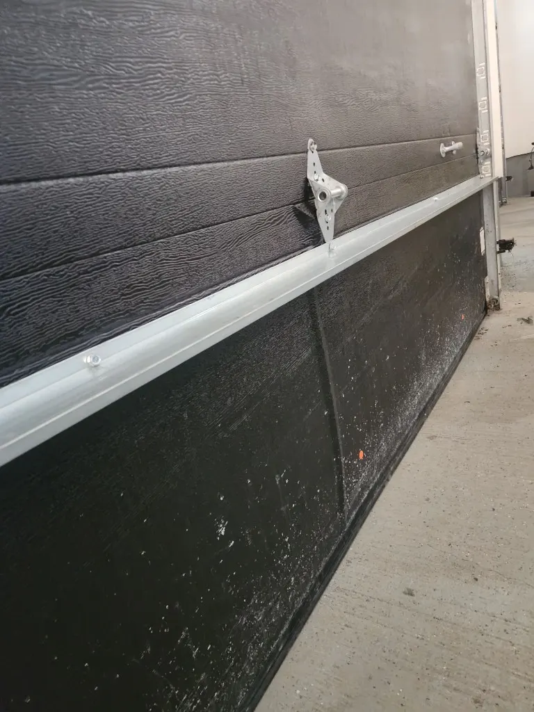Garage door panel straightened and reinforced with aluminum strut after impact damage in Ottawa