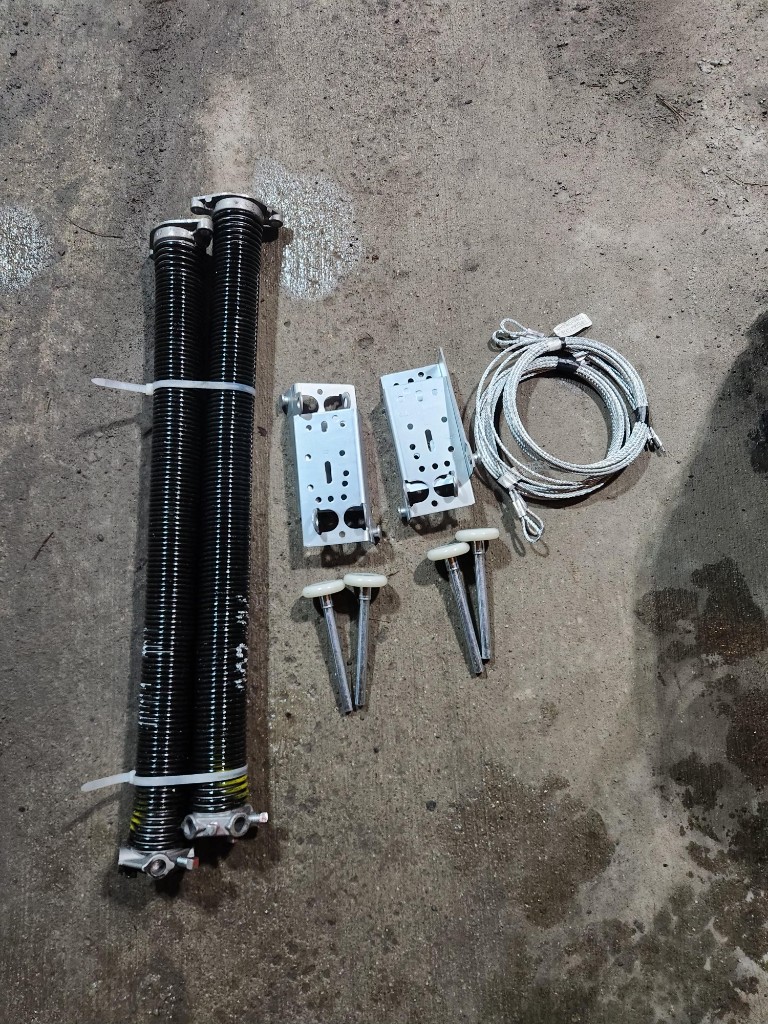 New torsion springs, brackets, rollers, and lift cables laid out for a garage door spring replacement in Ottawa