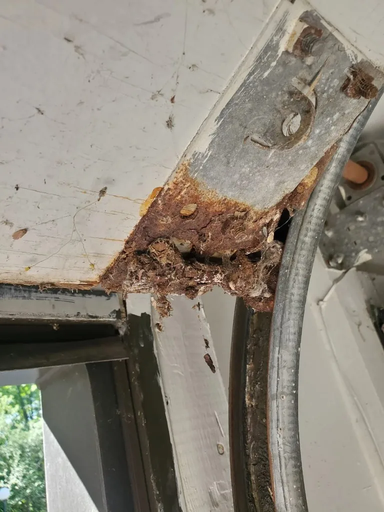 Rusted bottom bracket and corroded lift cable at the bottom corner of a Stittsville garage door